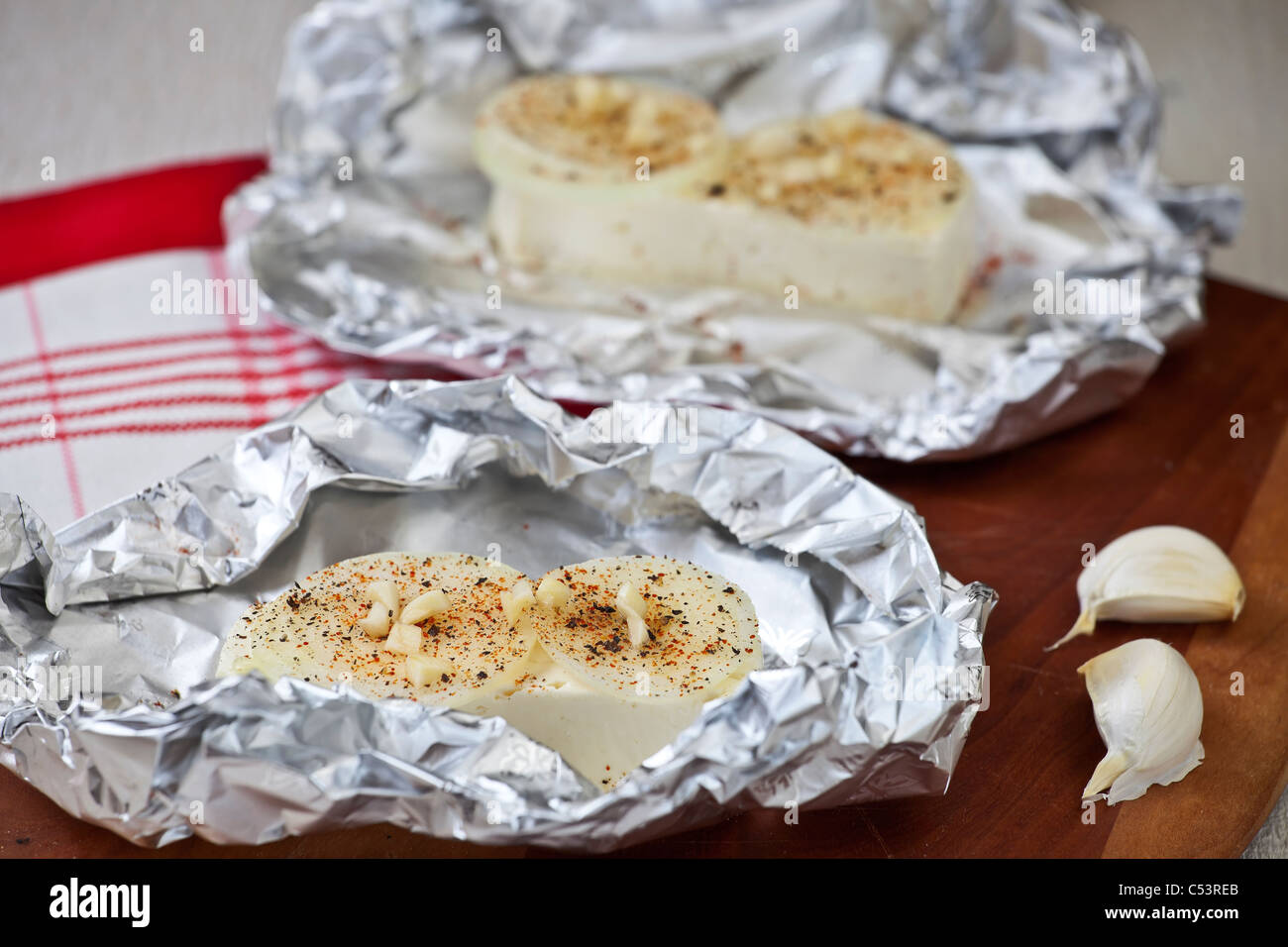Feta cheese in foil with onions, spices and garlic Stock Photo