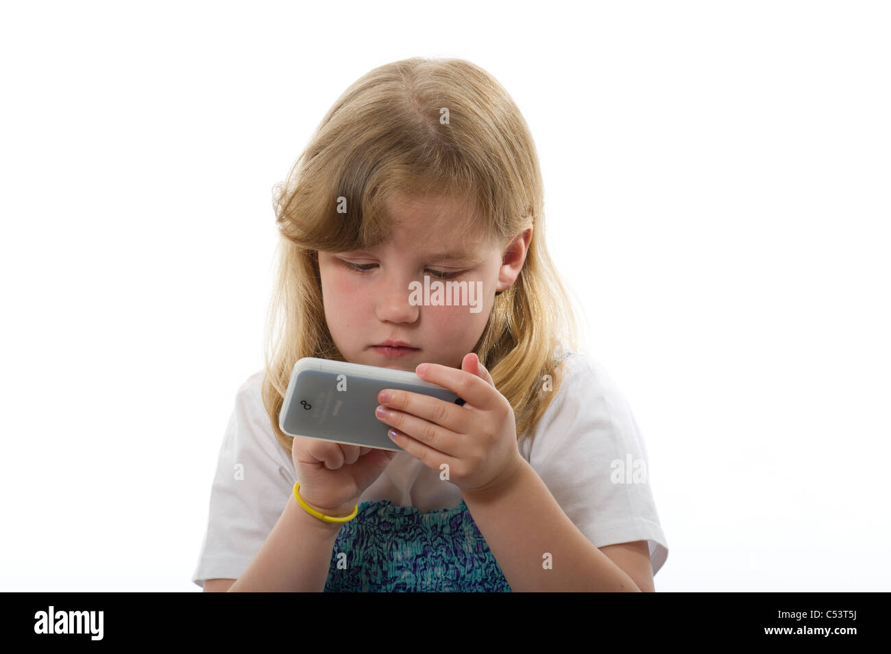 Girl of primary age playing with an iphone/ipod touch against a plain white studio background. Stock Photo