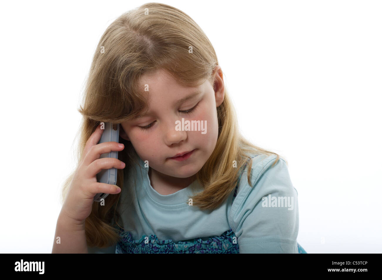 Image of young girl using a mobile phone photographed against a plain white background. Stock Photo