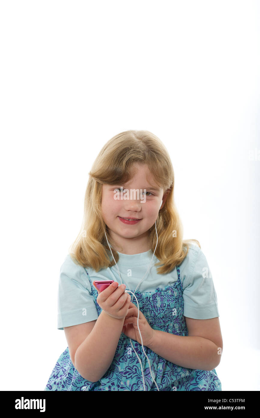 A young girl of 7 or 8 years listening to an ipod Nano/MP3 player against a plain white studio background. Stock Photo