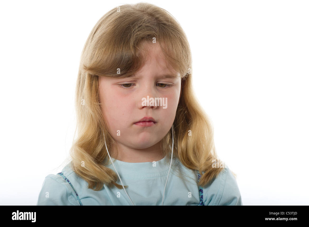 Young girl of primary age looking upset or unhappy against plain white studio background. Stock Photo
