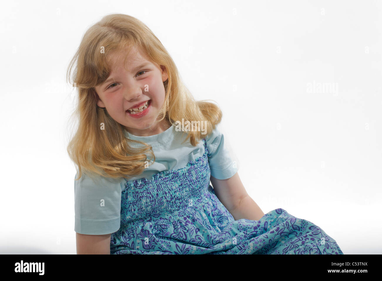 An image of young girl giggling and laughing against a plain white studio background. Stock Photo