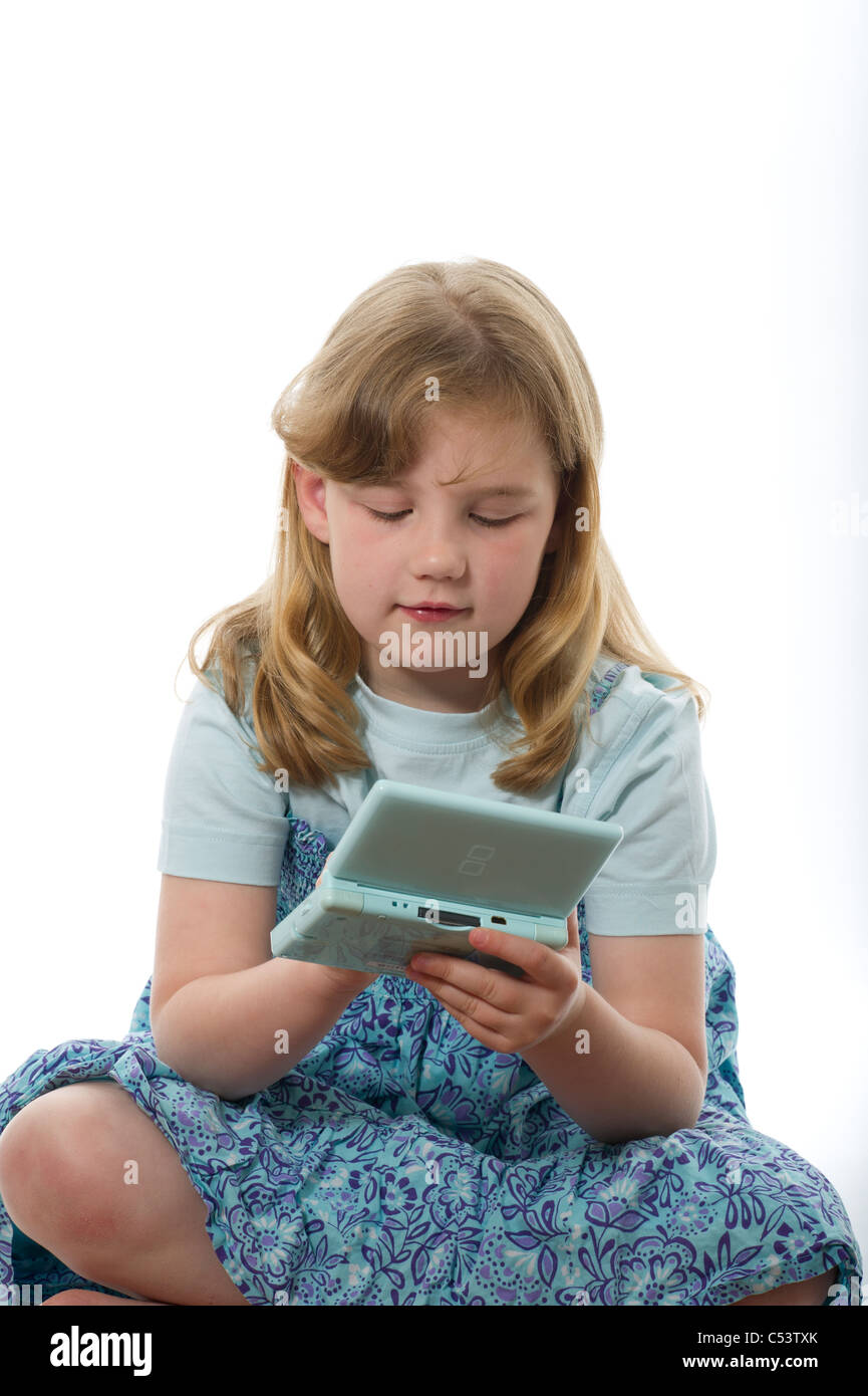 Young girl of primary age playing on a Nintendo DS game console, shot against a plain white studio background. Stock Photo