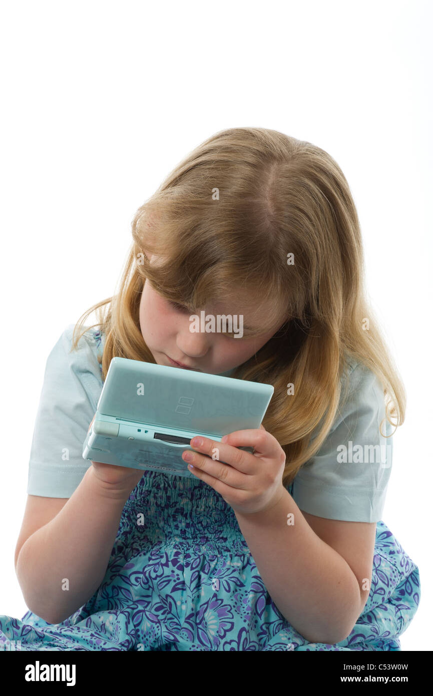 Young girl of primary age playing on a Nintendo DS game console, shot against a plain white studio background. Stock Photo