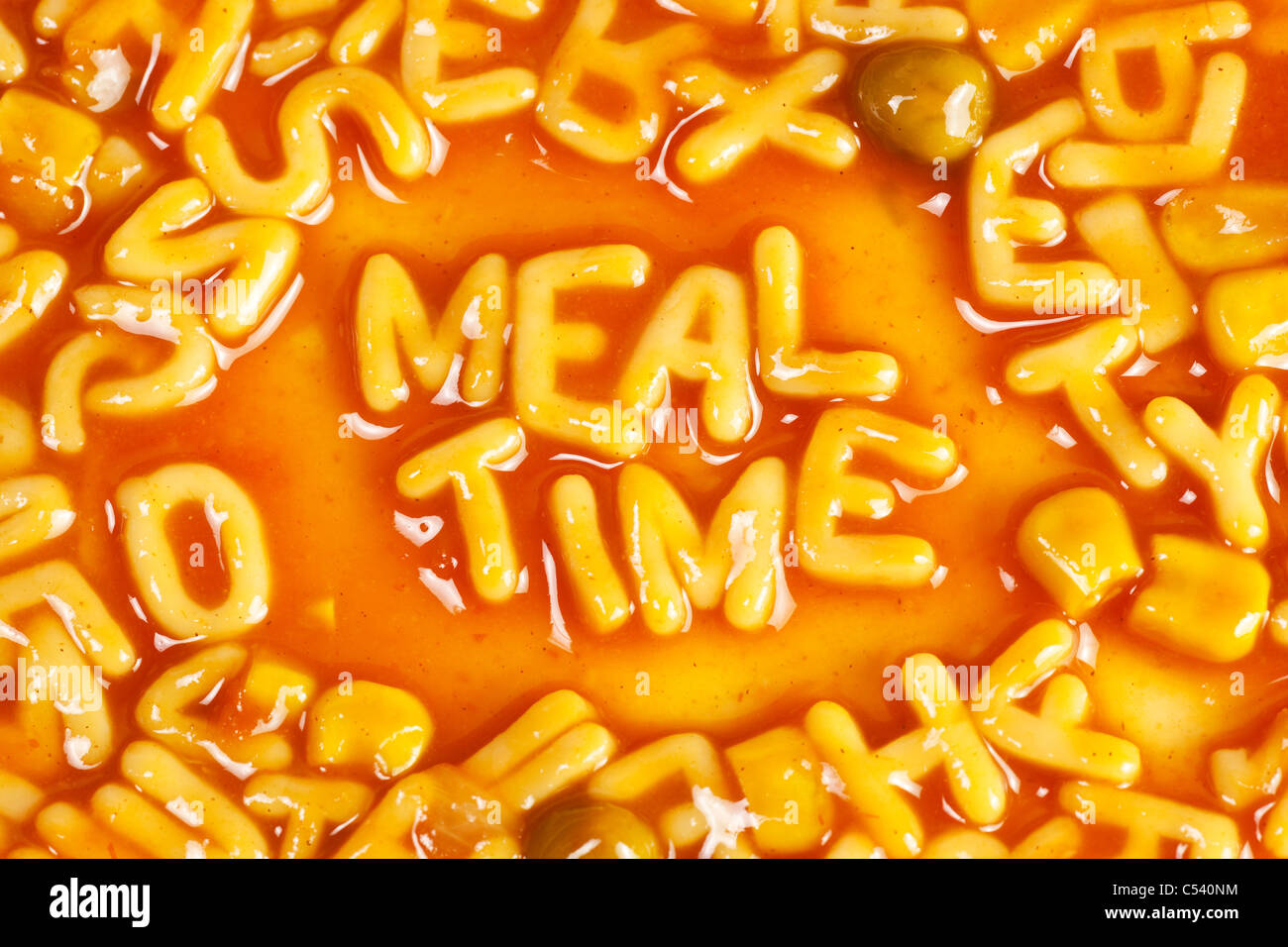 Alphabet shaped pasta forming the word MEALTIME in tomato sauce Stock Photo