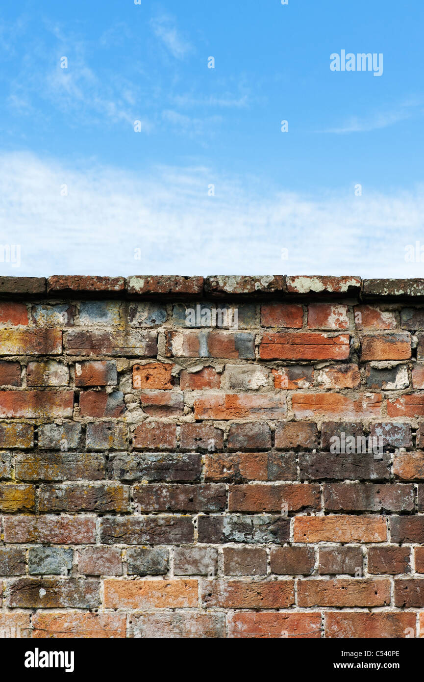 Old garden brick wall against a blue cloudy sky Stock Photo