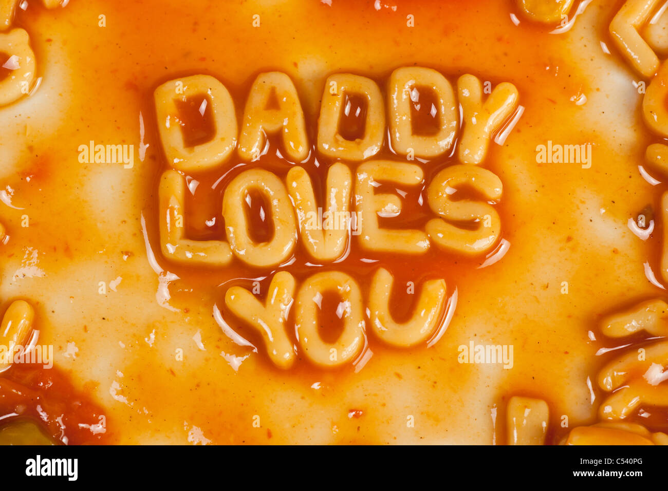 Alphabet shaped pasta forming DADDY LOVES YOU in tomato sauce Stock