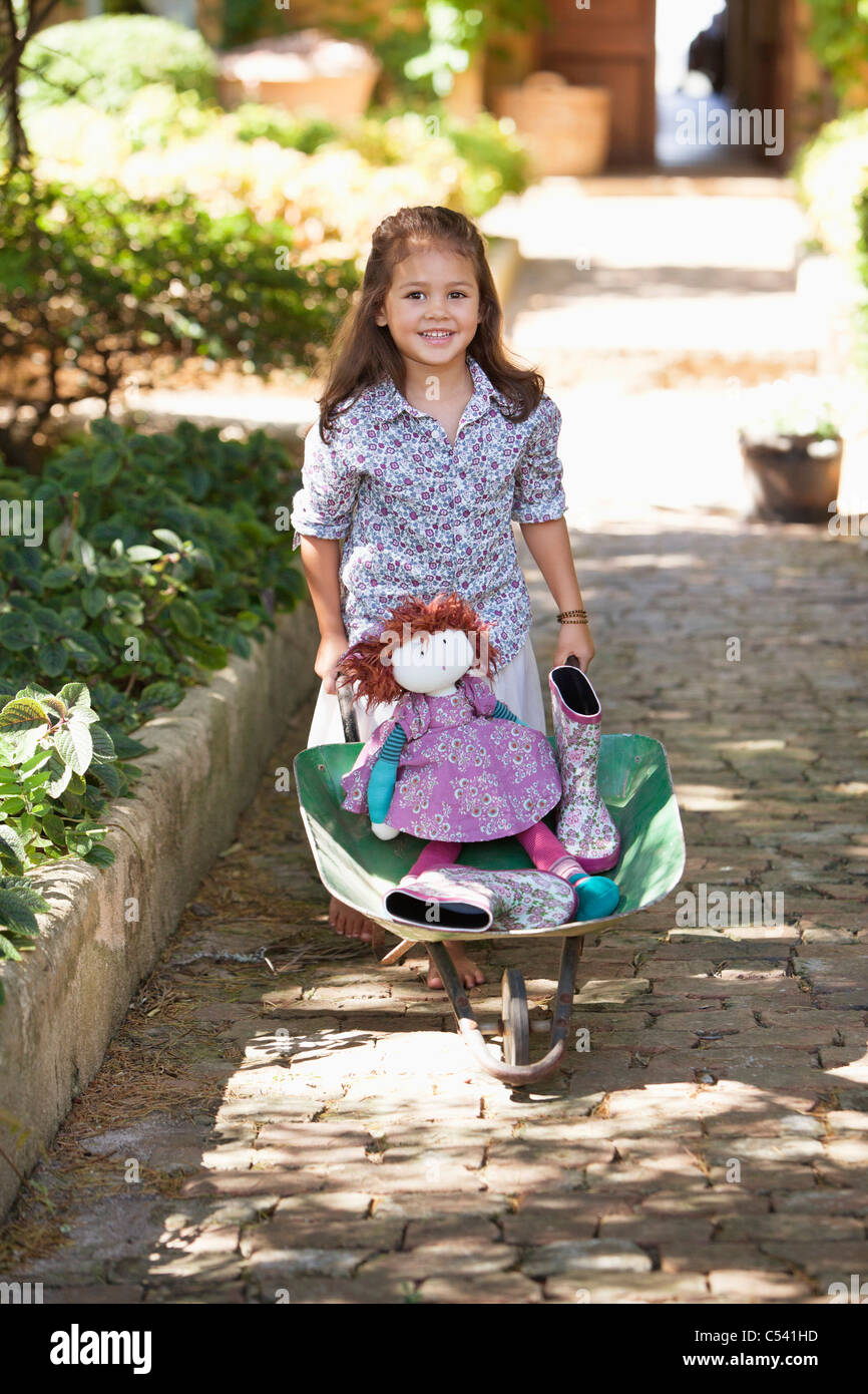 Cute girl pushing a wheelbarrow filled with toys Stock Photo - Alamy
