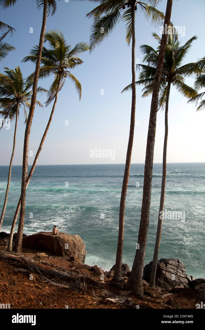 single tourist sitting between palmtrees and watching the sea at Mirissa, Sri Lanka Stock Photo