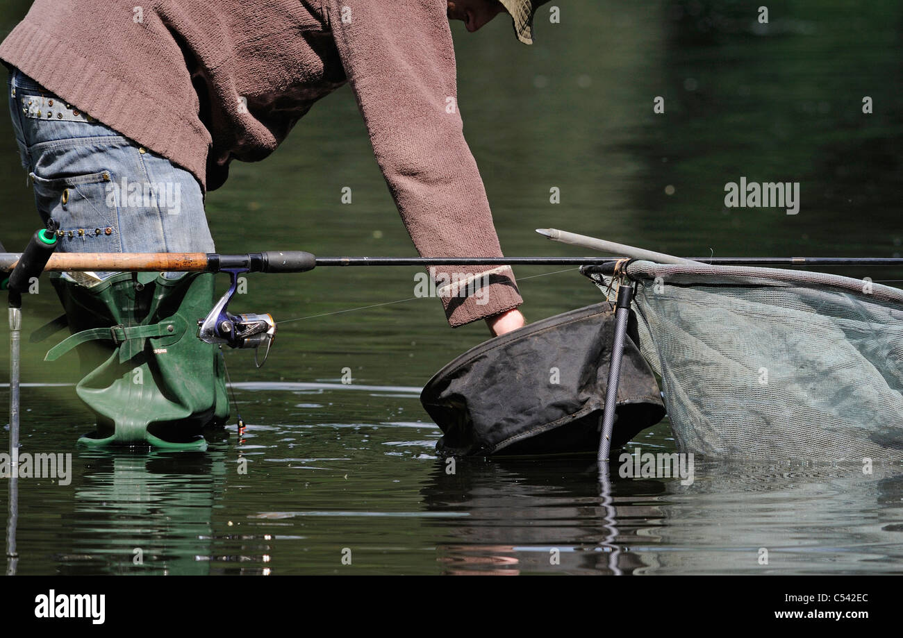 A fisherman fishing wearing waders and holding a fishing rod Stock Photo -  Alamy