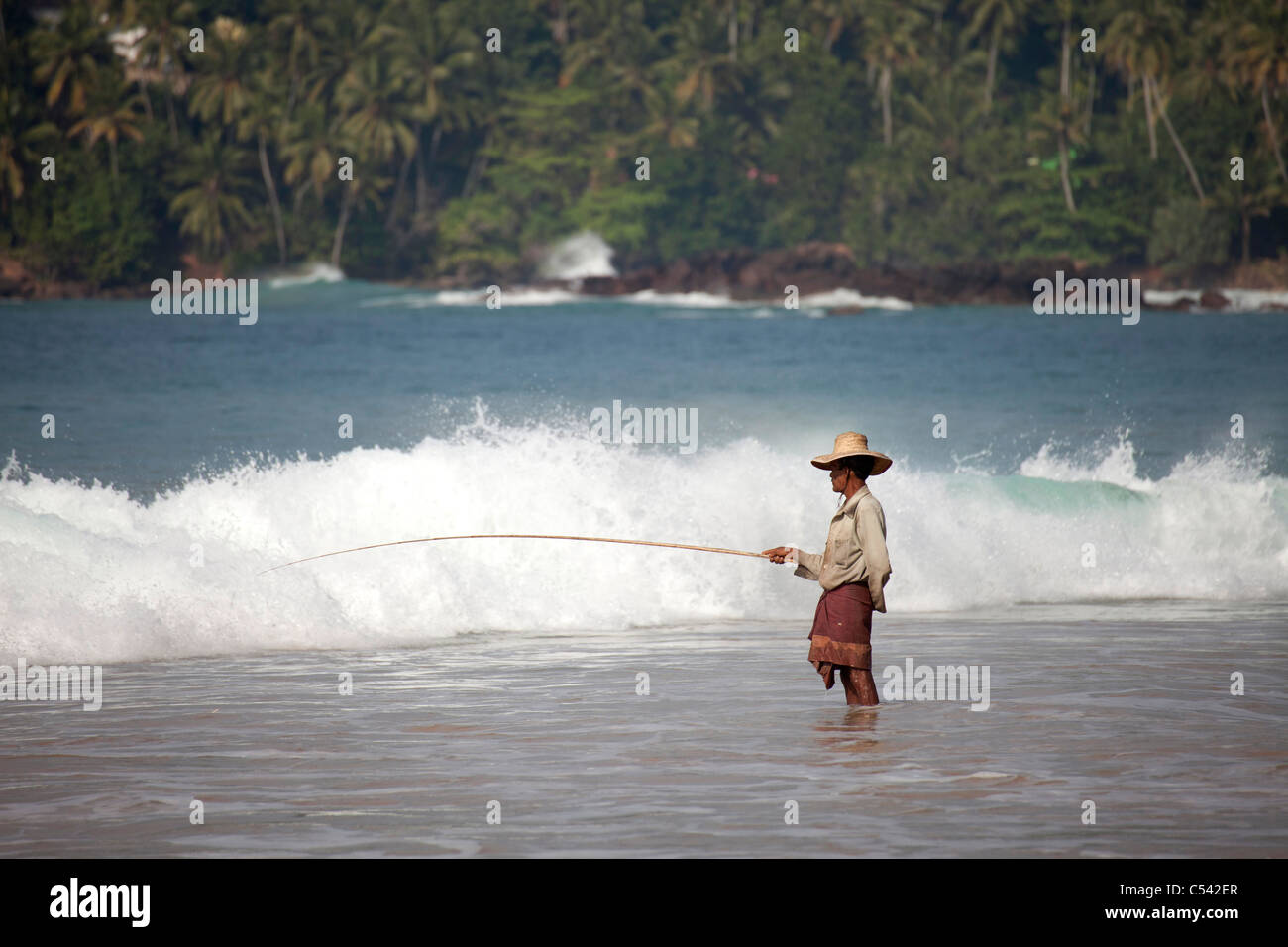 fisherman angling in the waves of Mirissa beach, Sri Lanka Stock Photo