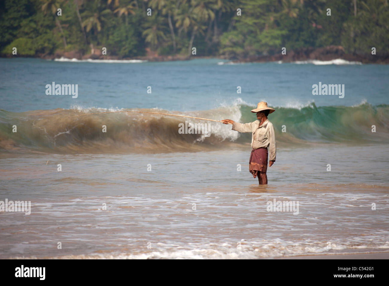 fisherman angling in the waves of Mirissa beach, Sri Lanka Stock Photo