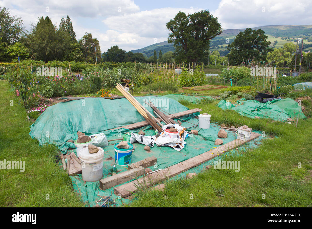 Plot covered with green plastic to suppress weed growth on community allotments in village of Llangattock Powys South Wales UK Stock Photo