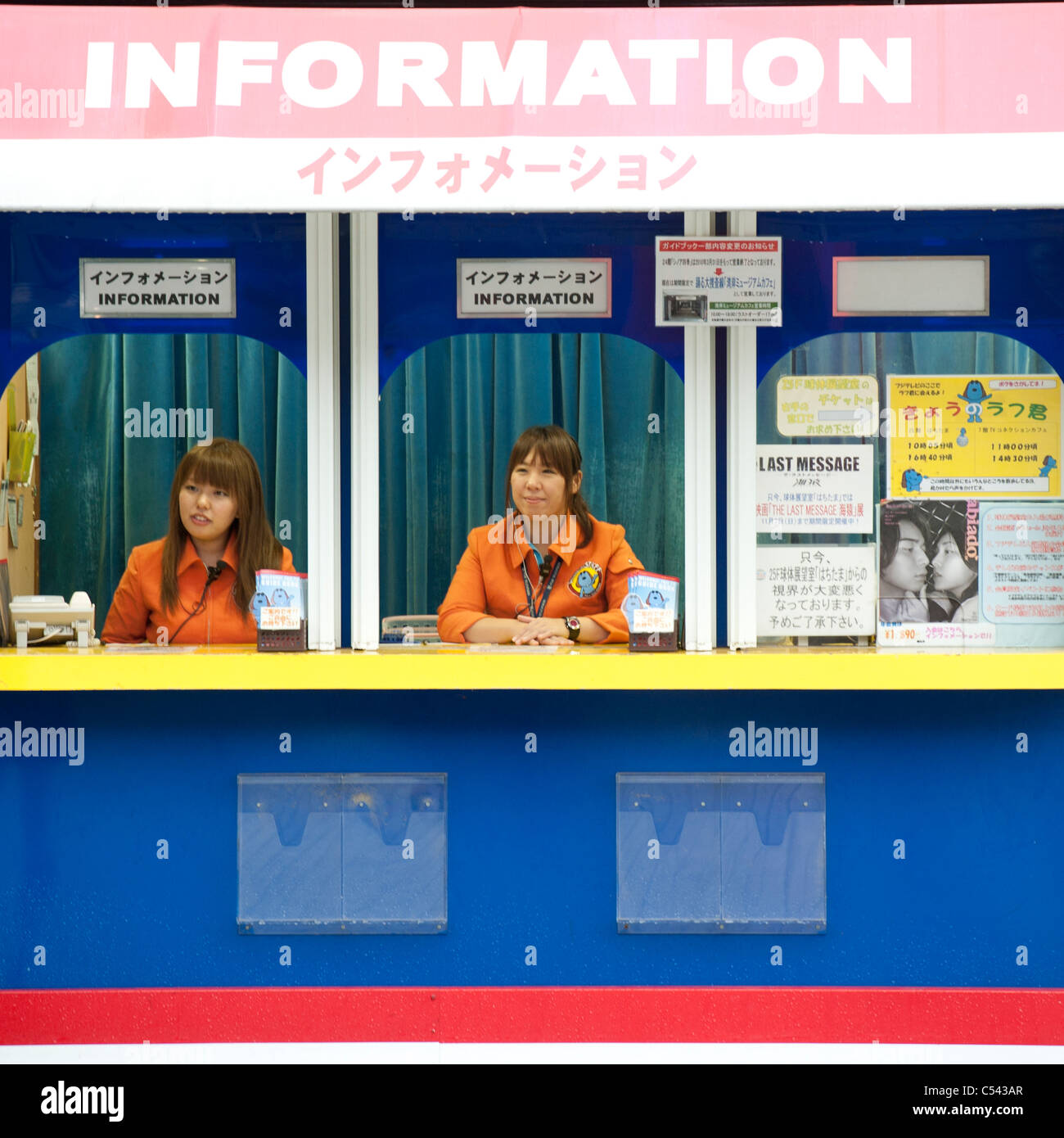 Two women sitting on a information counter, Odaiba, Minato Ward, Tokyo, Japan Stock Photo