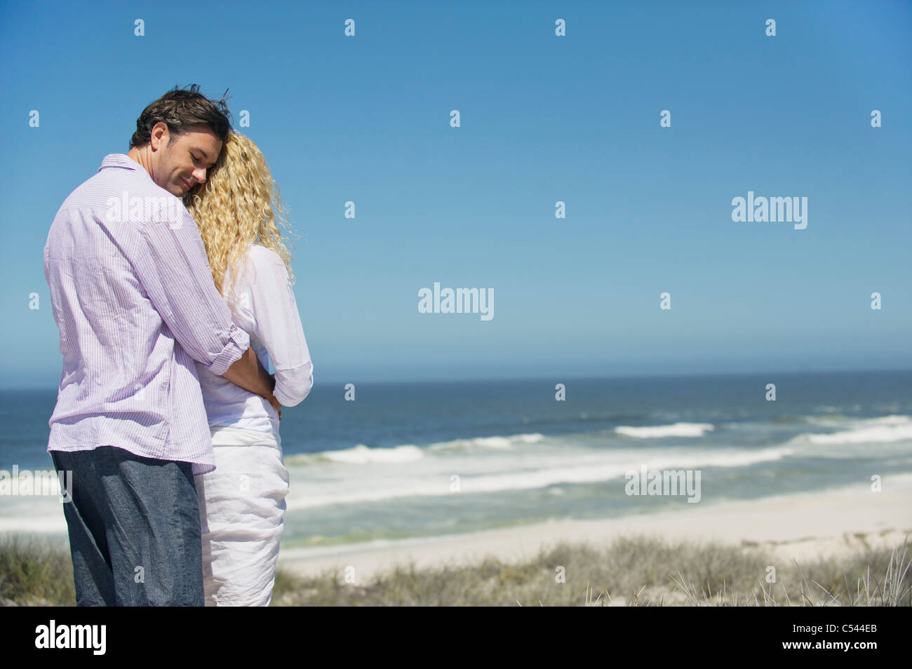 Man embracing a woman from behind on the beach Stock Photo - Alamy