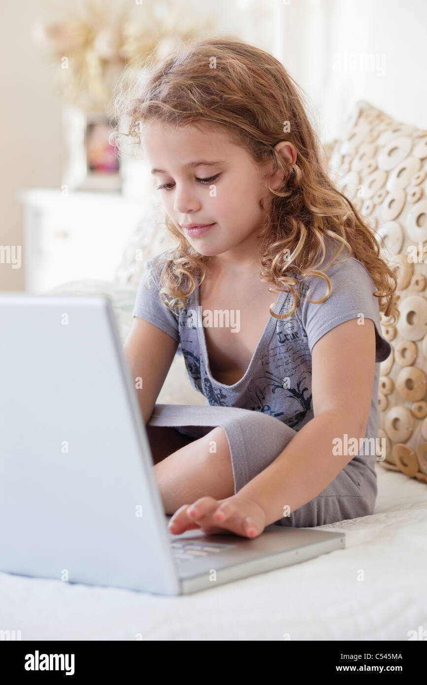 Cute little girl using a laptop in the bed Stock Photo - Alamy