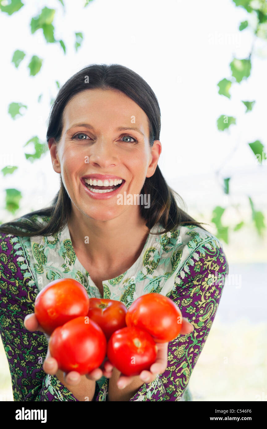 Portrait of a smiling mature woman holding tomatoes Stock Photo - Alamy