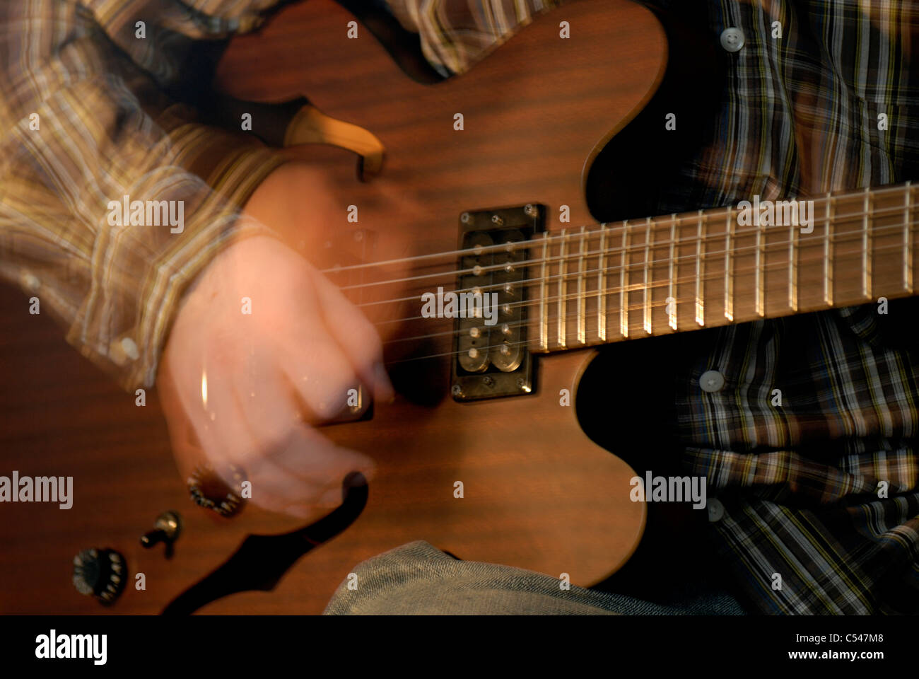 A hollow body electric guitar being strummed, with motion blur Stock Photo