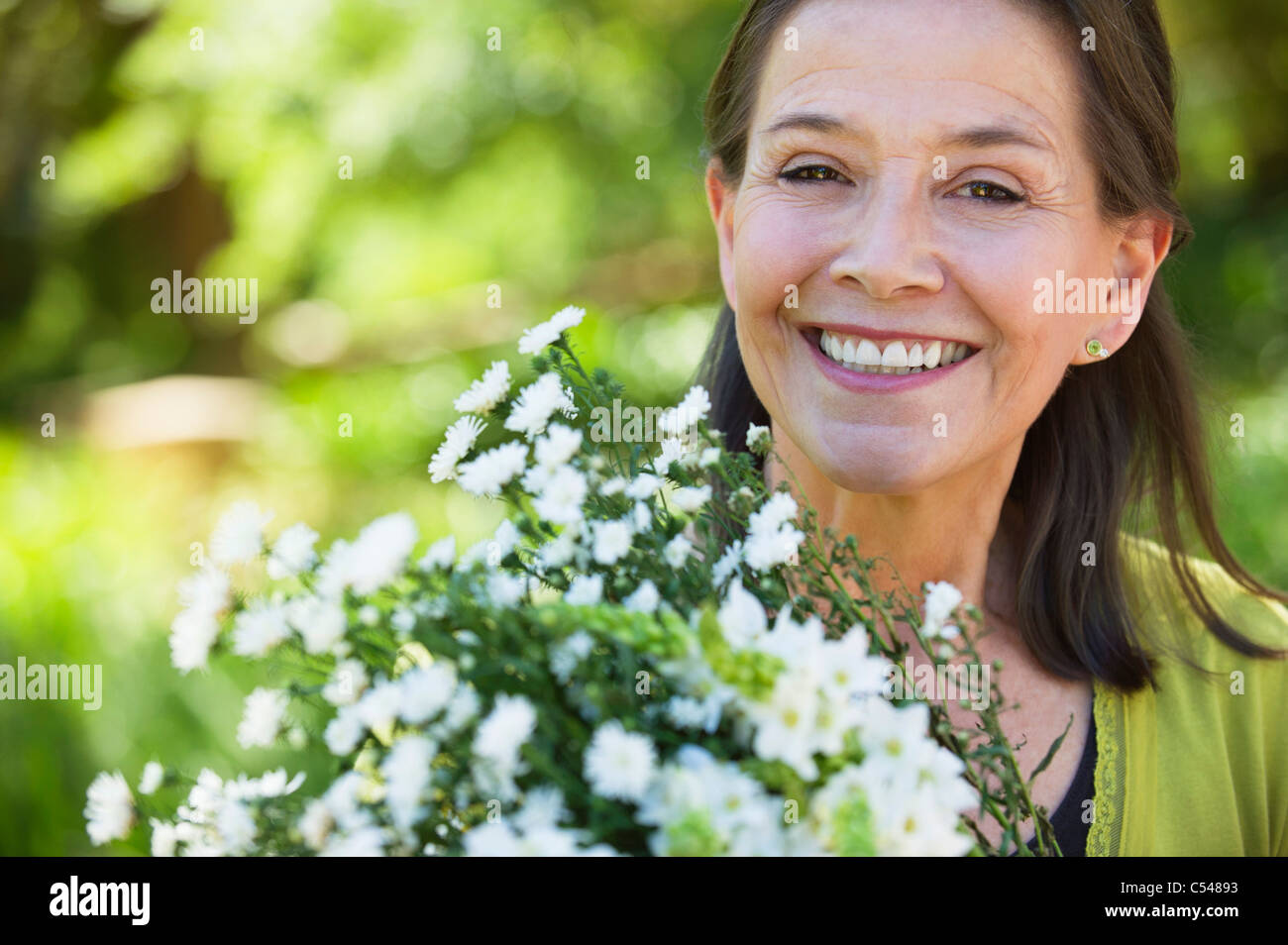 Portrait of a woman holding a bunch of flowers outdoors Stock Photo - Alamy
