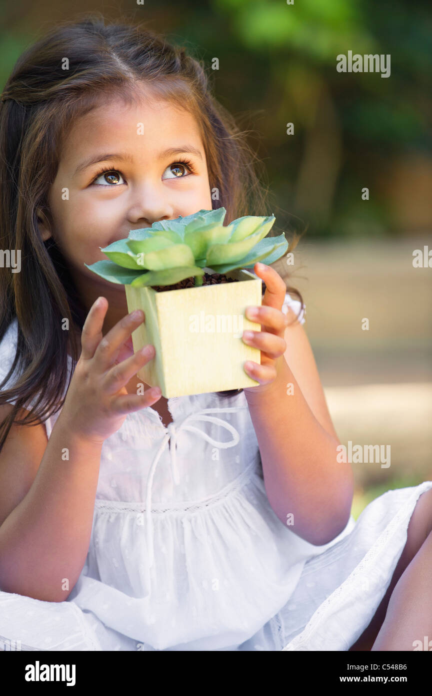 Cute little girl holding a potted plant and looking up Stock Photo - Alamy