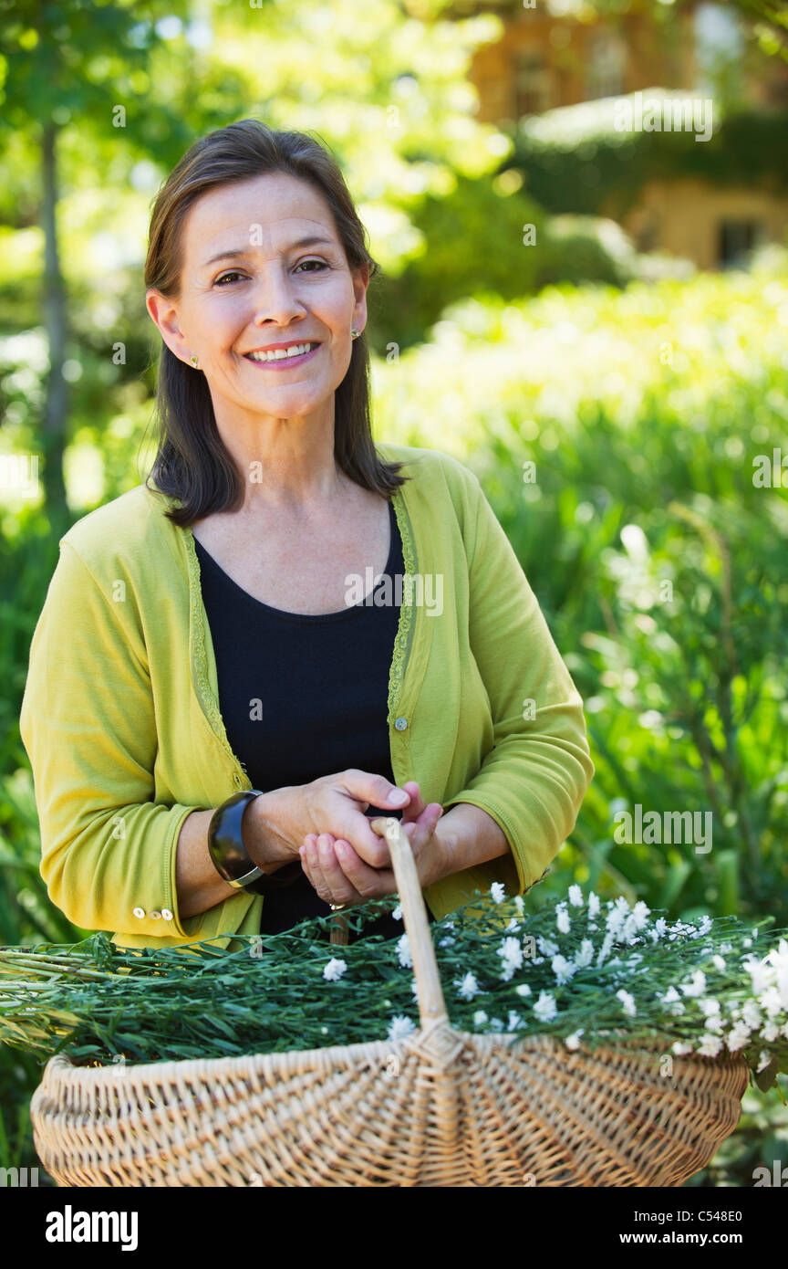Portrait of a woman holding basket of flowers outdoors Stock Photo - Alamy