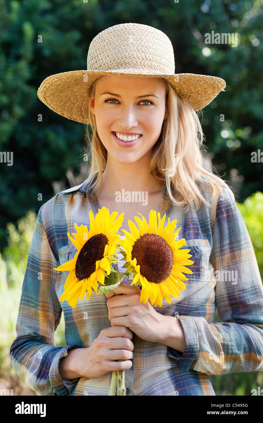 Portrait of a young woman holding sunflowers in a field Stock Photo - Alamy