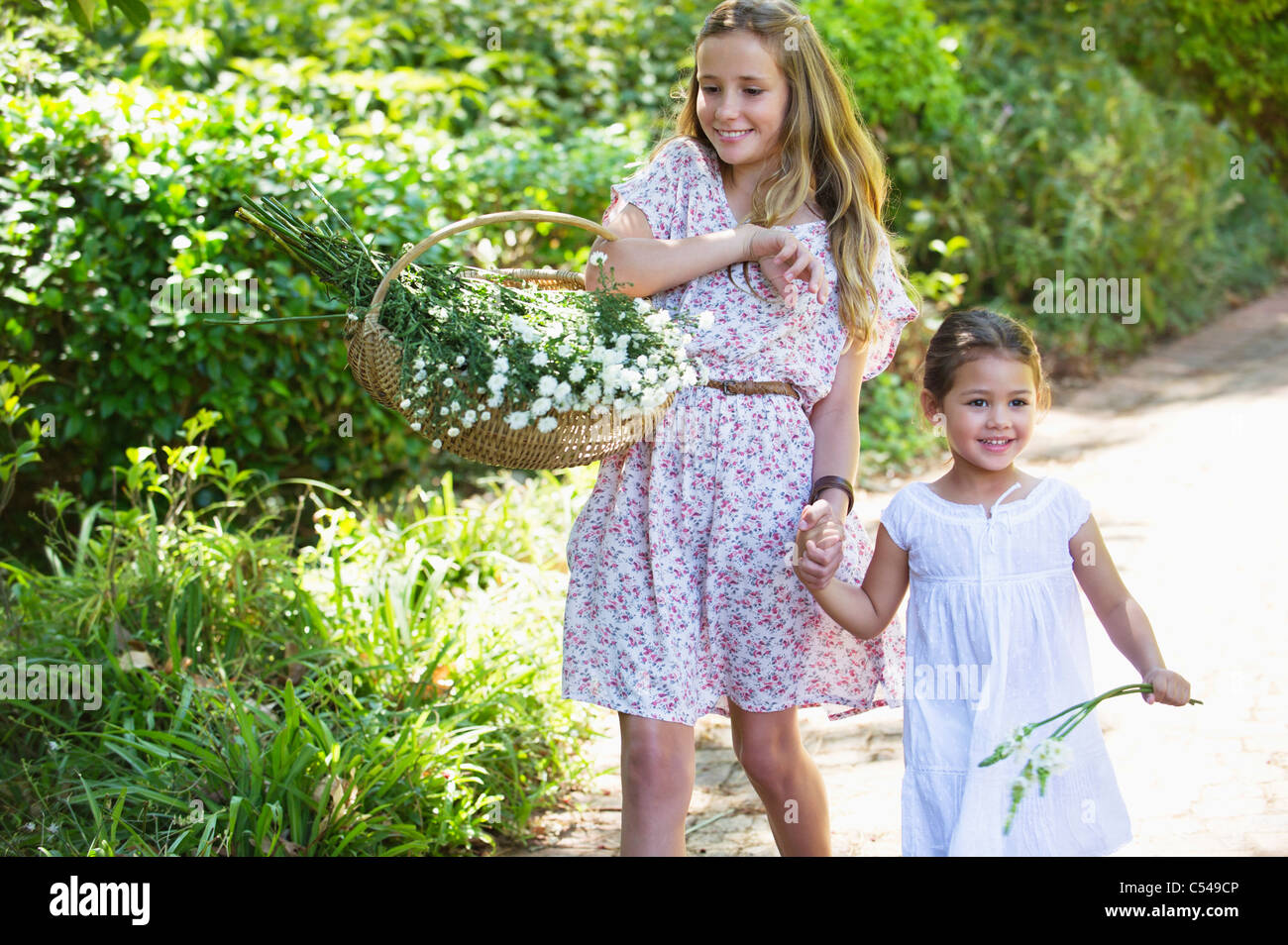 Happy siblings walking holding hands in garden Stock Photo - Alamy