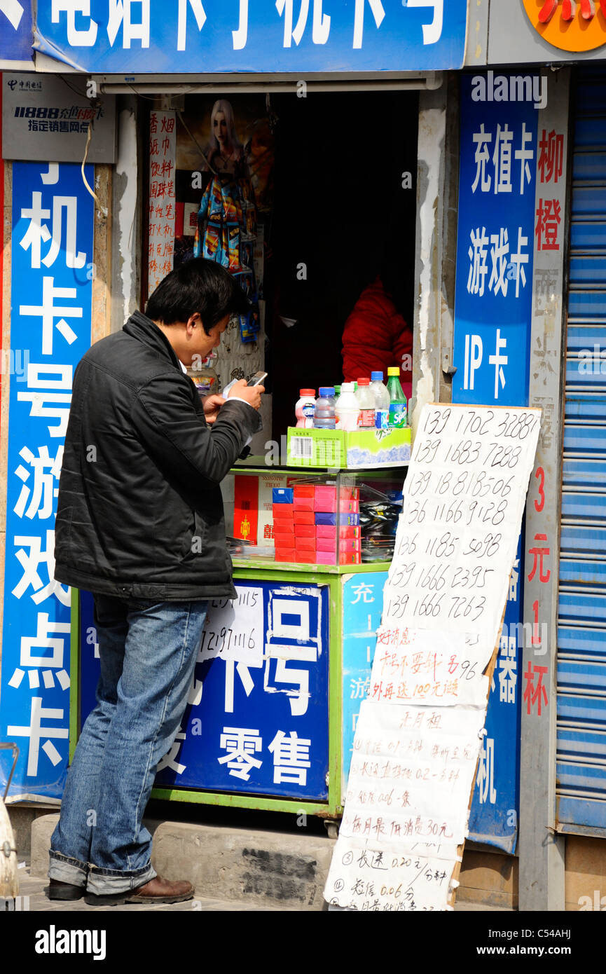 A Chinese man using a mobile phone in old town Shanghai Stock Photo