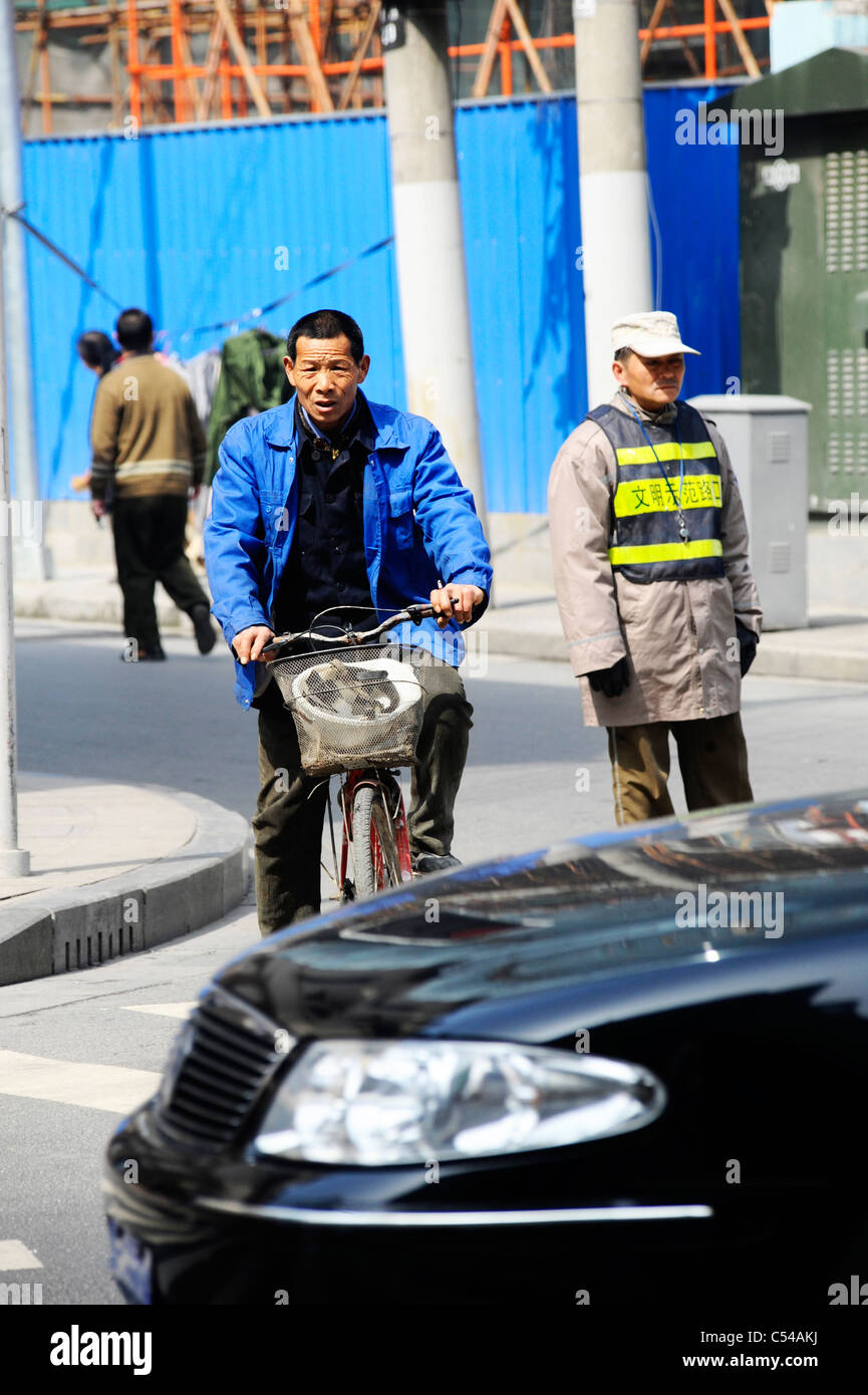 A chinese man riding his bike at a junction in Shanghai Stock Photo