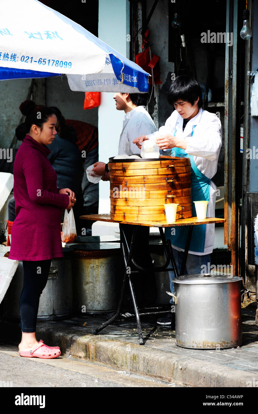 Woman buying steamed dumplings in Shanghai old town. Stock Photo