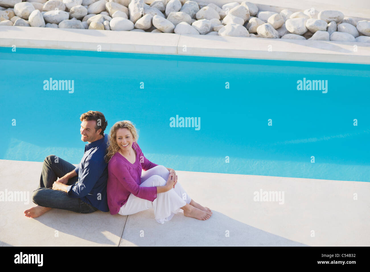 Two women sitting by the side of a swimming pool hi-res stock ...