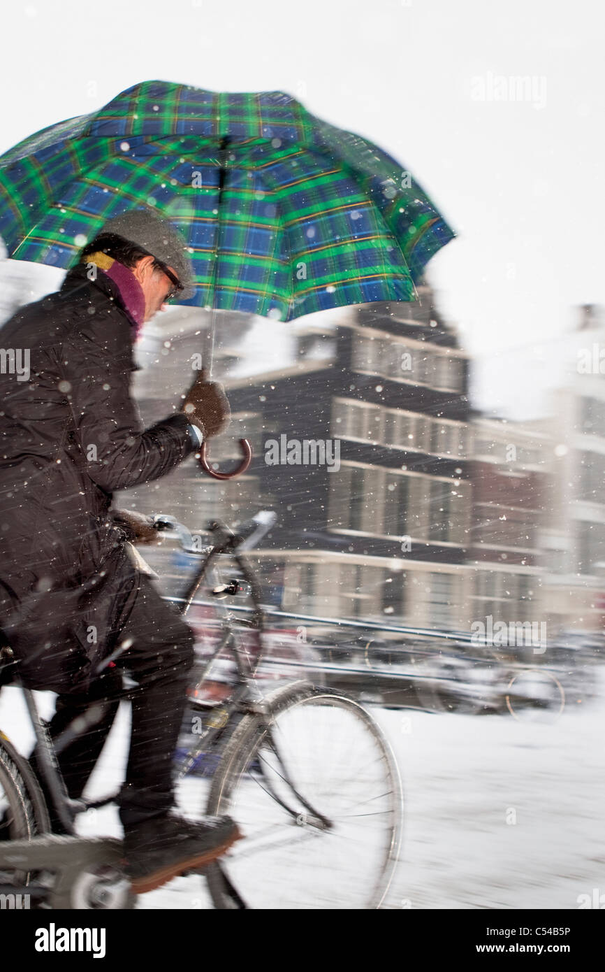 The Netherlands, Amsterdam, 17th century houses at canal called Keizersgracht. Winter, snow, cyclist. Stock Photo