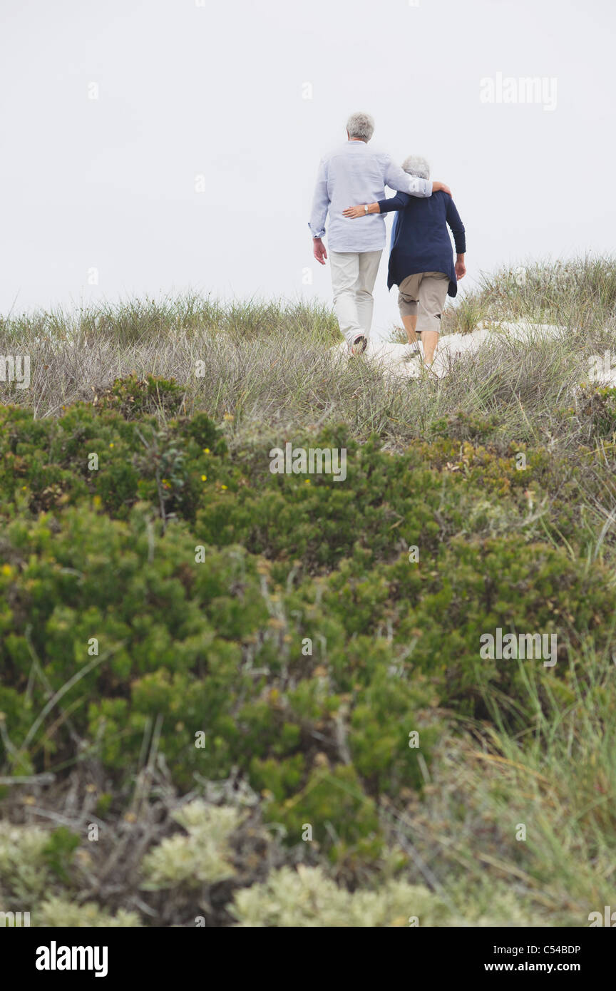 Rear view of a senior couple walking on the beach with their arms around each other Stock Photo