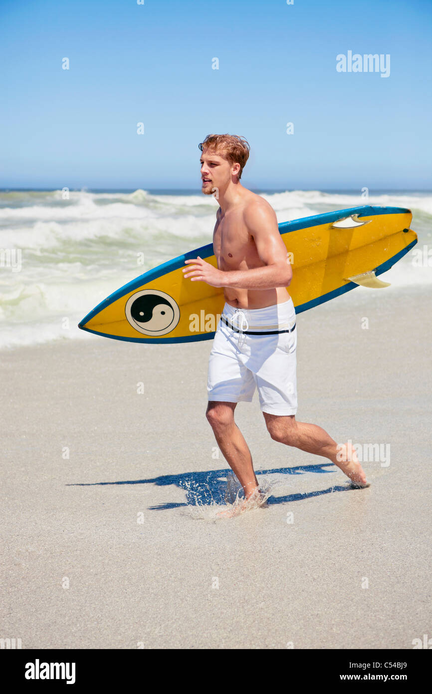 Man running on the beach with surfboard Stock Photo - Alamy