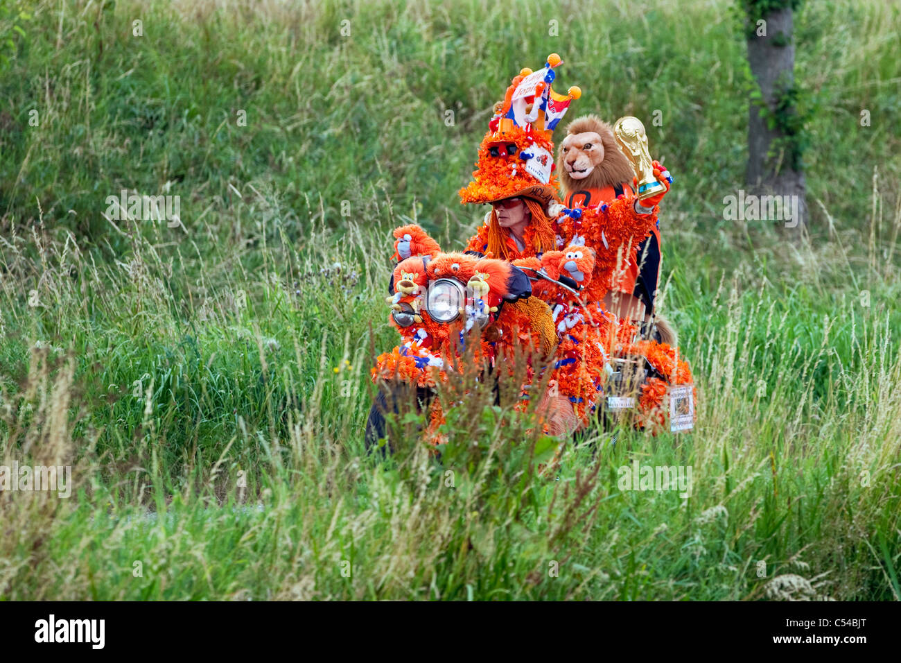 World Cup Football July 2010. Motorcycle and driver decorated in orange, supporter Dutch national team. Holding replica of cup Stock Photo