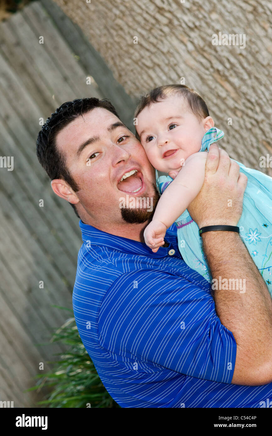 A father plays with his 8 month old baby girl outdoors. Stock Photo