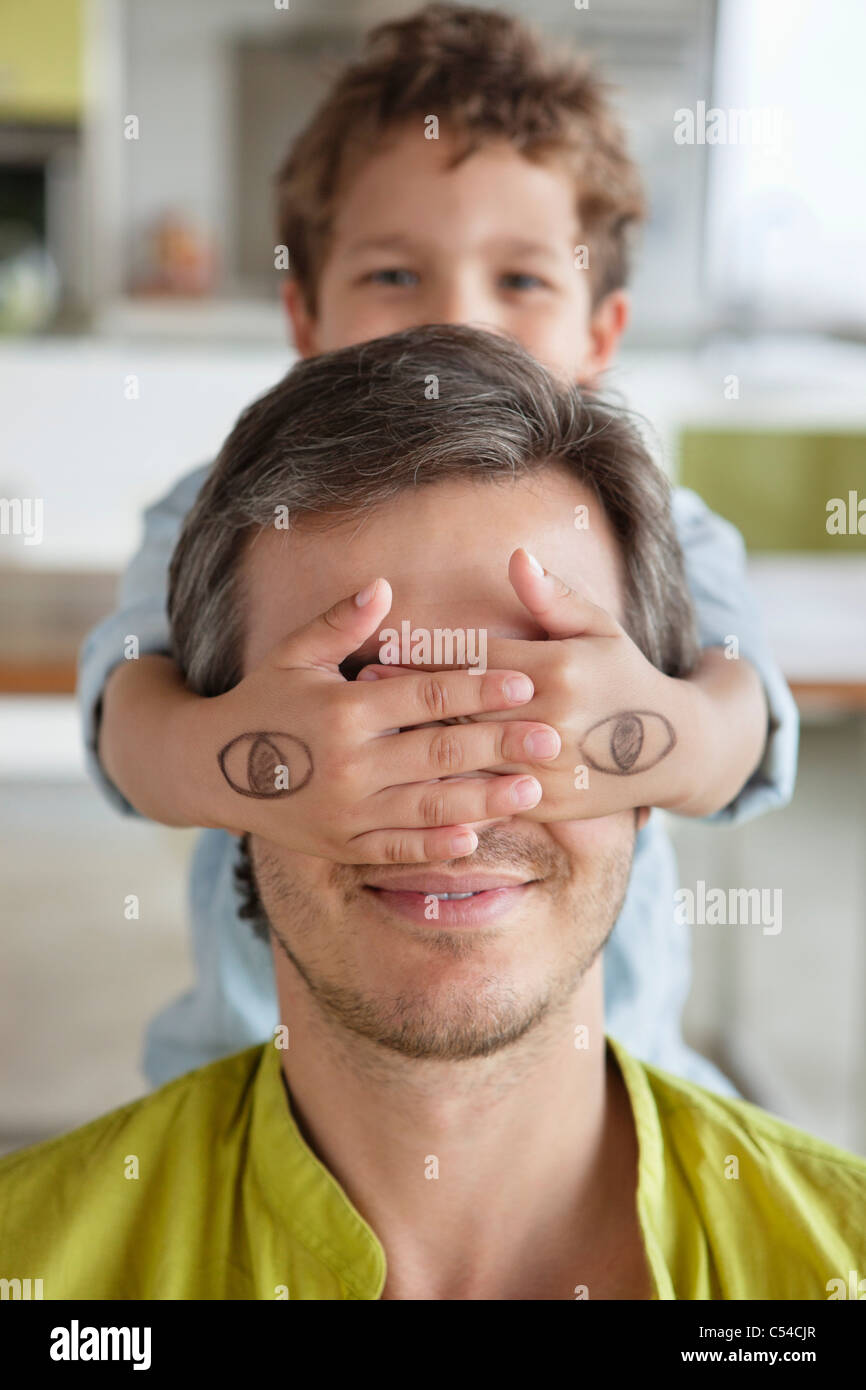 Boy covering his father's eyes Stock Photo - Alamy