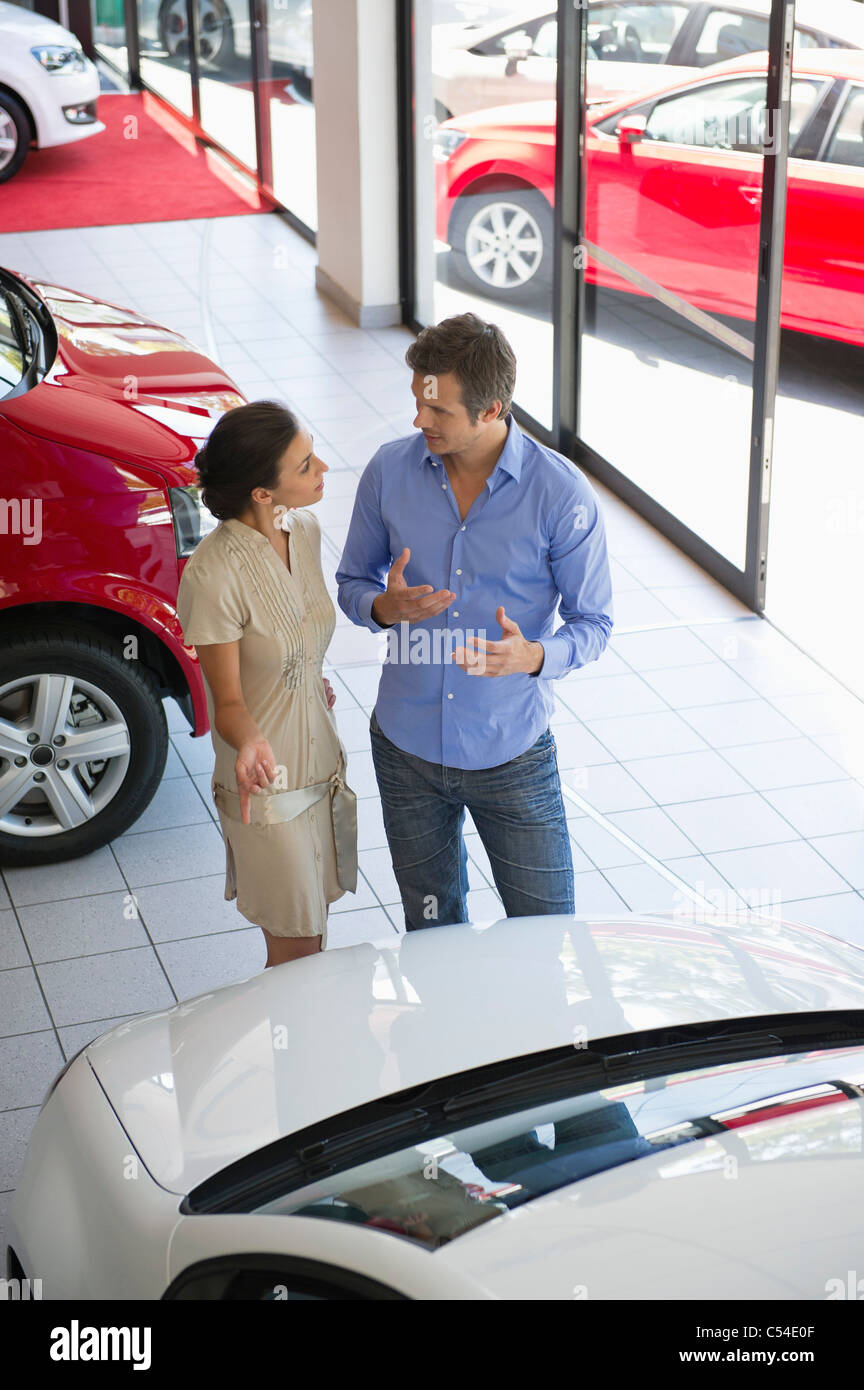 Female salesperson showing car to mid adult man in showroom Stock Photo