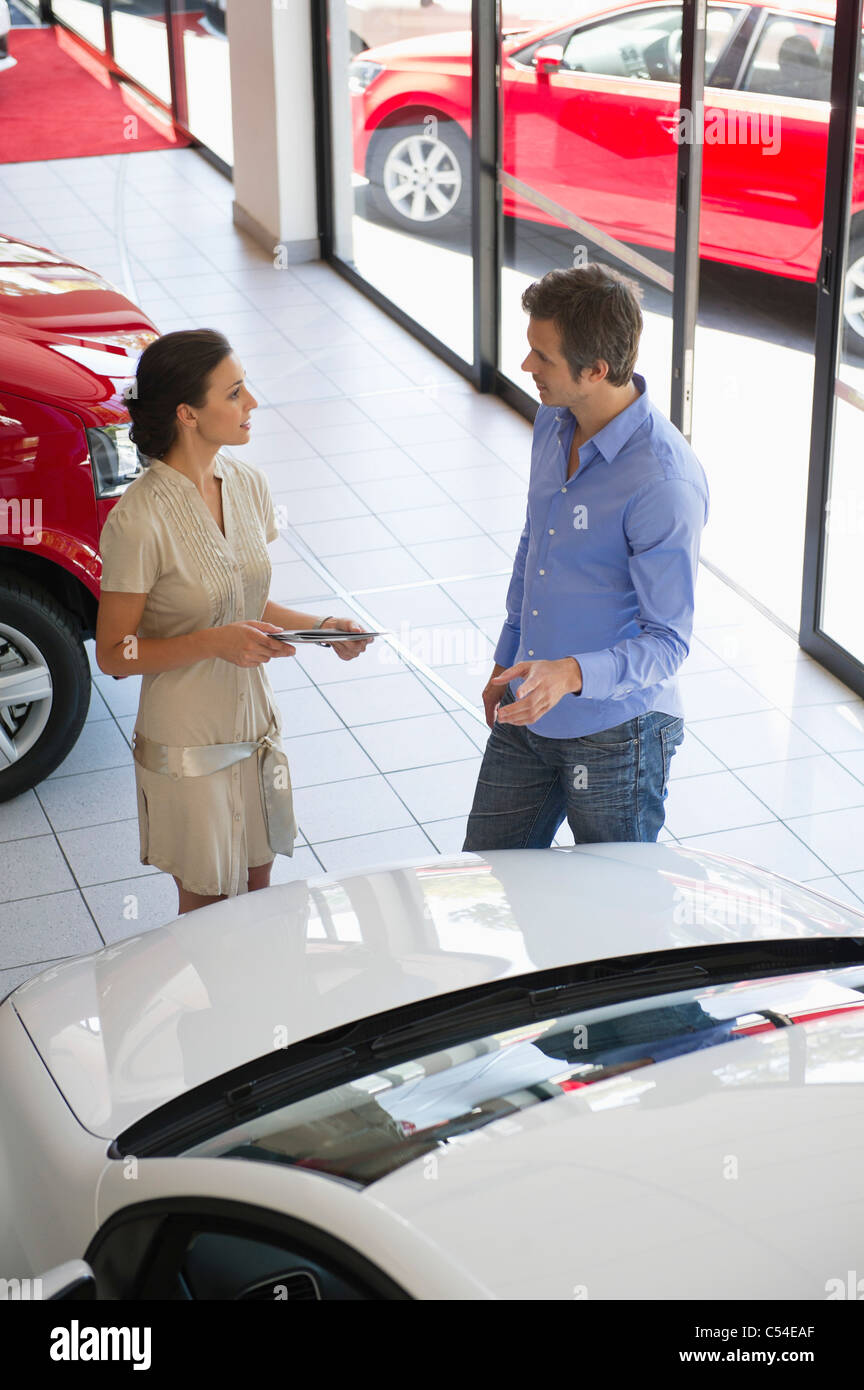 Female salesperson showing car to mid adult man in showroom Stock Photo