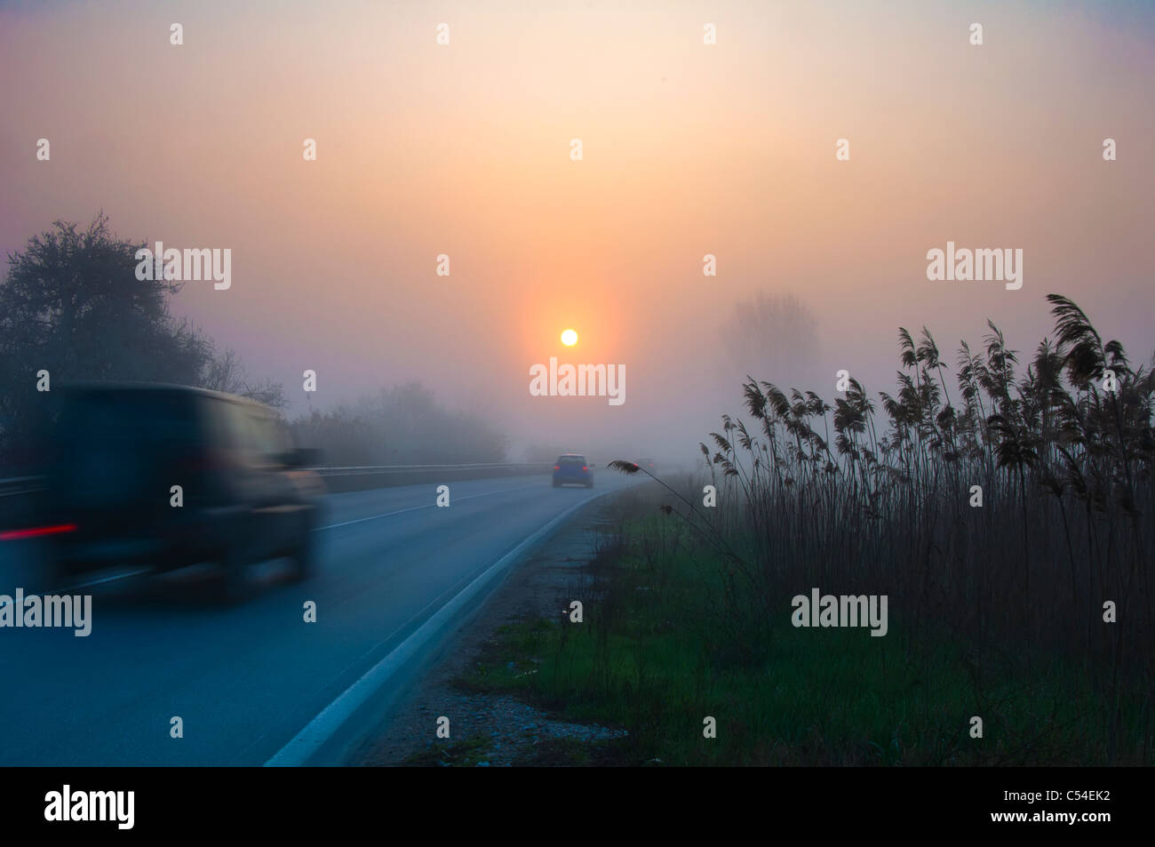 Road in fog with cars, early morning sunrise Stock Photo - Alamy