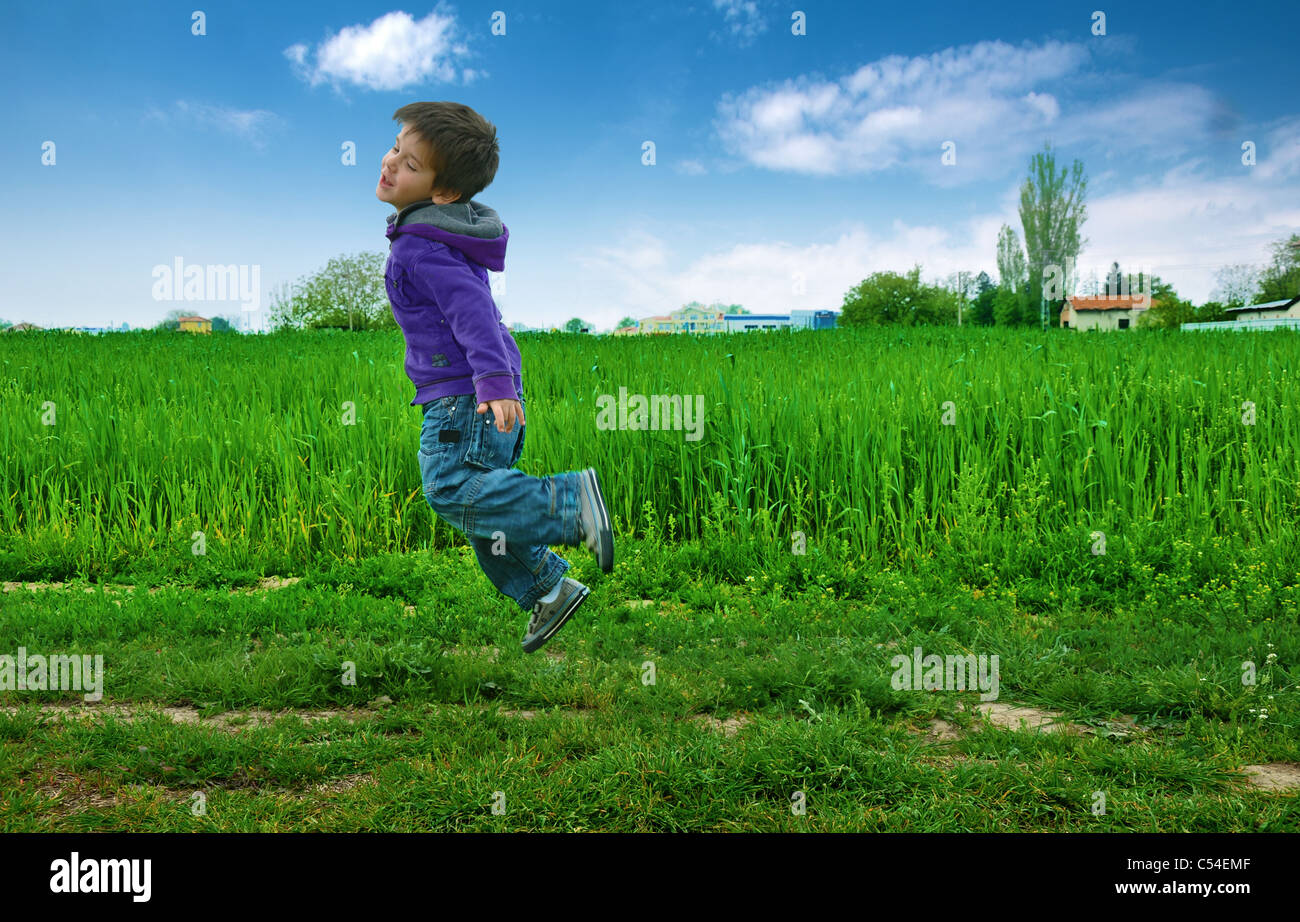 Jumped boy on green meadow, blue sky Stock Photo