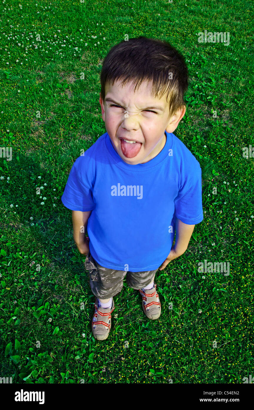 Young boy tongue sticking on green meadow Stock Photo
