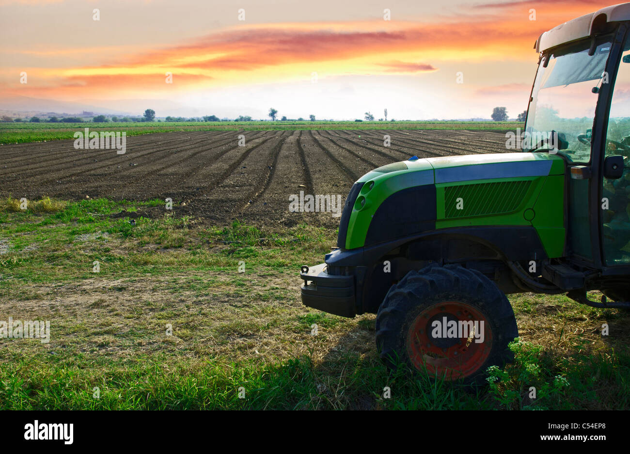 Plowed land and tractor on sunset Stock Photo - Alamy