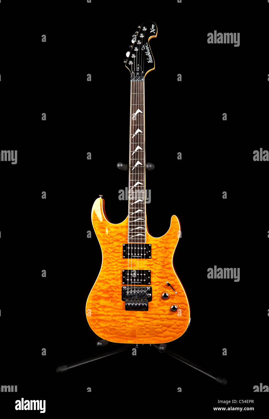 Yellow electric guitar with guitar stand on black background. Stock Photo