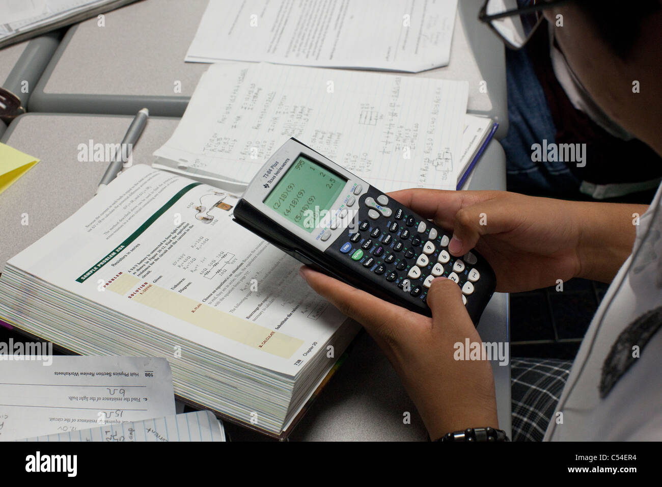 Student uses graphing calculator to help solve problem in textbook during class in El Paso, Texas high school classroom Stock Photo