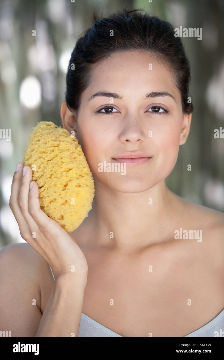 Beautiful young woman holding a bath sponge on her face Stock Photo Alamy