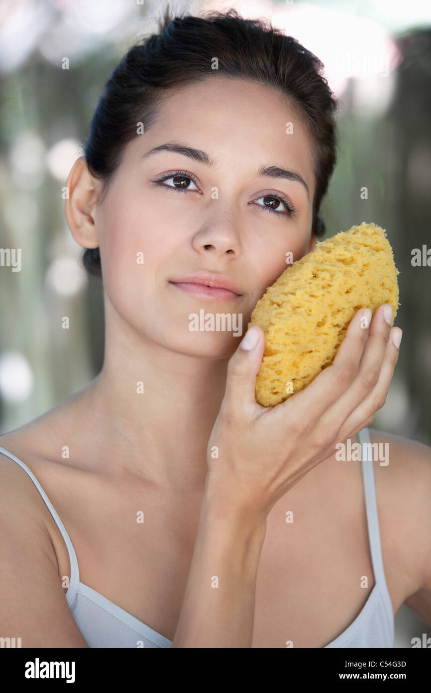 Beautiful young woman holding a bath sponge on her face Stock Photo Alamy