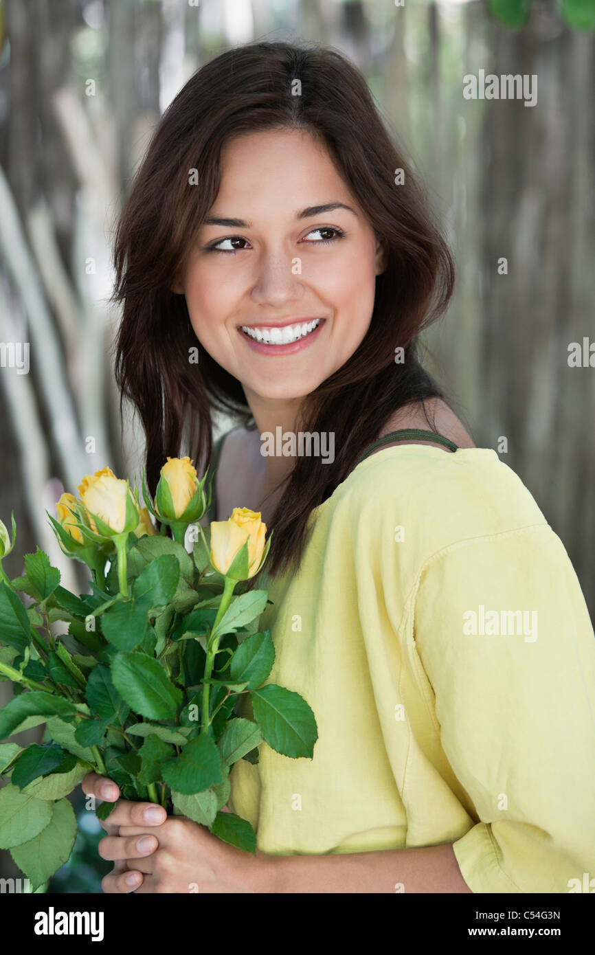 Young woman holding bunch of yellow flowers and smiling Stock Photo - Alamy