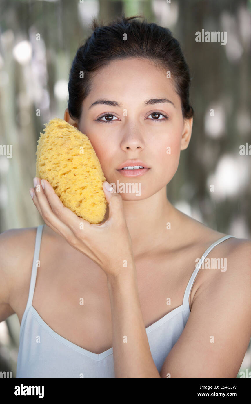 Beautiful young woman holding a bath sponge on her face Stock Photo Alamy