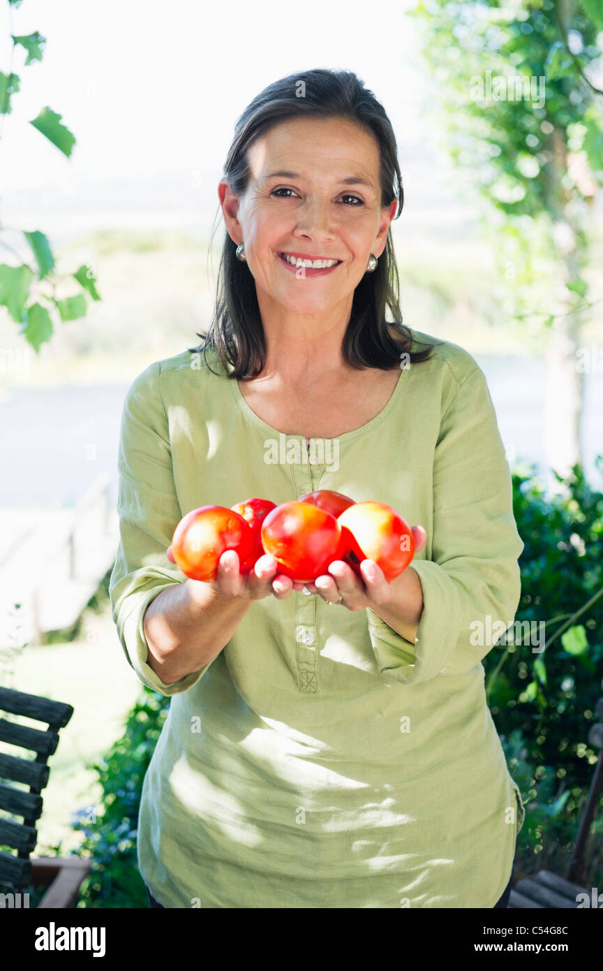 Portrait of a senior woman holding tomatoes Stock Photo - Alamy